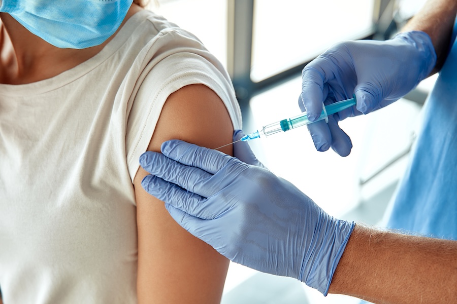 In a modern clinic, a healthcare worker administers a vaccine to a masked patient, creating a safe and clean environment that enhances the experience for both the patient and caregiver